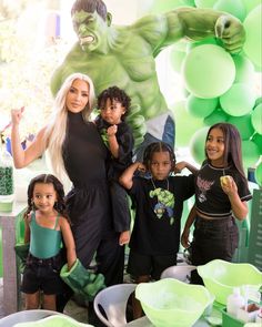 a group of children standing next to each other in front of a hulk man backdrop