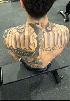 the back of a man's neck with tattoos on his chest and arms, sitting on a bench