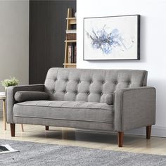 a gray couch sitting on top of a hard wood floor next to a book shelf