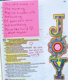 an open bible with the word joy written in colorful letters on it and a pink background