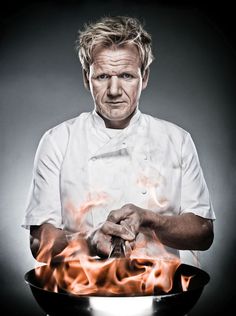 a man in white shirt holding a frying pan with flames on it