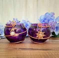 two purple bowls sitting on top of a wooden table