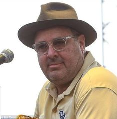 a man in a hat and glasses is holding a microphone