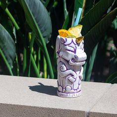 a purple and white ceramic cup with a drink in it sitting on top of a cement block