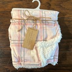 a pink and white plaid blanket with a tag hanging from it's hanger