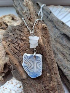 a blue and white necklace on a piece of driftwood with sea shells in the background