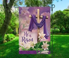 a purple banner with flowers and a cross on it in the middle of a field