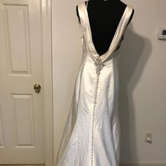 the back of a white wedding dress hanging on a hanger in front of a door