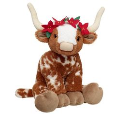 a brown and white stuffed cow with red bows on it's head sitting down