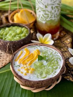 two bowls filled with food sitting on top of a table next to flowers and palm leaves