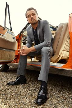 a man sitting in the back of a car with his foot propped on the door