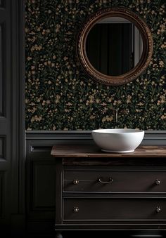 a bowl is sitting on a dresser in front of a wallpapered room with a mirror