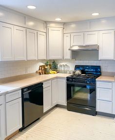 a kitchen with white cabinets and black appliances