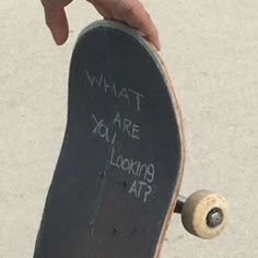 a person holding a skateboard with writing on the bottom and bottom part that says, what are you looking at?