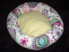 a small dog bed with colorful designs on it's sides and a yellow pillow in the middle