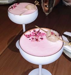 two desserts with pink icing and flowers on them are sitting on pedestals