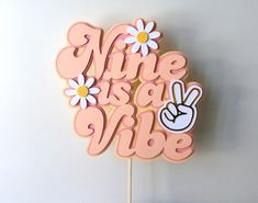 a cake topper that says mine is a vibe with daisies and a peace sign