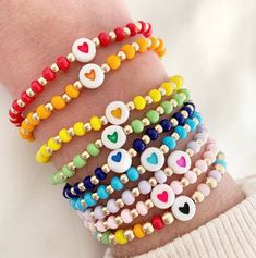 a woman's arm with several bracelets that have hearts and other charms on them