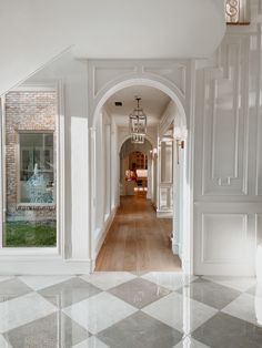 an archway leading to a living room with white walls and wood flooring on both sides