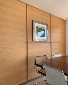 an empty conference room with wooden paneling and leather office chairs, framed artwork on the wall