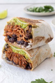 two burritos stacked on top of each other with black beans and guacamole