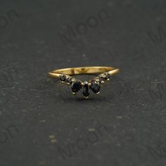 a gold ring with three black stones on it, sitting on a dark surface in front of the camera