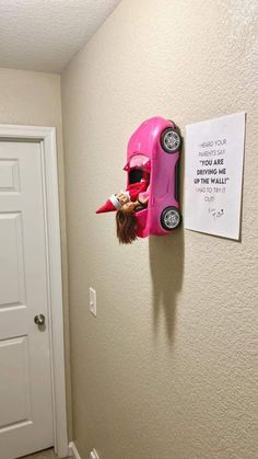 a pink toy car mounted to the side of a wall next to a white door