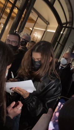 a woman wearing a face mask while standing in front of a group of other people