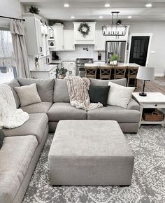 a living room filled with furniture and a large ottoman in front of a kitchen area