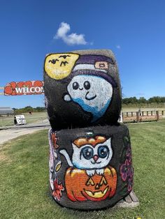 two pumpkins with faces painted on them in front of a welcome sign