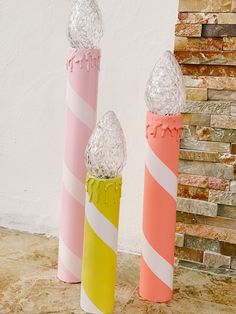 three candy canes sitting next to each other in front of a brick wall