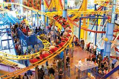 an indoor amusement park with people riding the roller coasters and other rides in it