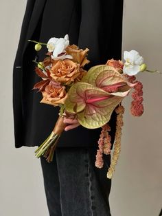 a person in a suit holding a bouquet of flowers on their lapel, and wearing a black blazer