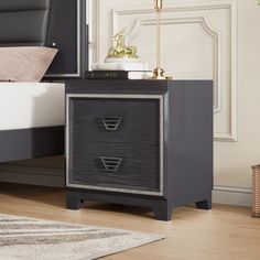 a night stand with two drawers and a mirror on top of the dresser next to a bed