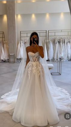 the woman is taking a selfie in her wedding dress while looking at her phone