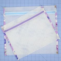 three pieces of white fabric with purple and blue trims on top of a cutting board