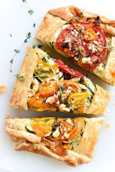 three slices of vegetable tarts on a white surface next to some breadsticks