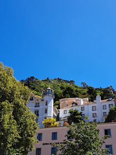 an apartment building on top of a hill with trees in the foreground and blue sky above