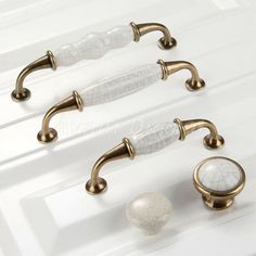 four different handles and knobs on a white counter top with marble balls in the middle