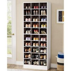 a white shoe rack filled with lots of pairs of shoes next to a door in a room