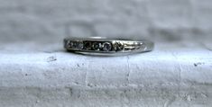 This Art Deco Vintage Diamond Channel Wedding Band is a classic - and would make a great wedding band or stackable today. Crafted in 18K White Gold, the band features 7 Single Cut Diamonds, approximately 0.21ct in weight, of excellent H/VS1 quality, all Channel Set, with a lovely Art Deco Floral Shoulders, and engraving. Beautiful and sparkly! Other Important Details: The band is a Size 4.75. The band is stamped '18K', and has been tested to be 18K White Gold. The band weighs 1.9 grams. The band Timeless Stackable Wedding Bands, Classic Stackable Diamond Wedding Ring, Classic Stackable Diamond Ring For Wedding, Classic Stackable Wedding Eternity Band, Formal Adjustable Stackable Rings With Diamond Accents, Classic Wedding Stackable Rings In Platinum, Classic Bands With Single Cut Diamonds For Promise Ring, Classic Cubic Zirconia Bands For Anniversary, Classic Stackable Wedding Bands