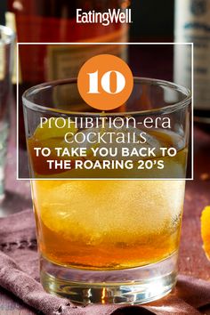 a glass filled with alcohol sitting on top of a table next to an orange slice