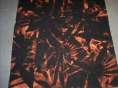 an orange and black tie dyed cloth on a tablecloth covered in brown fabric,