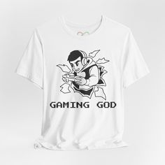 Elevate your gaming style with our "Gaming God" t-shirt! This sleek tee features an eye-catching black and white line art image of a boy deeply engaged in his favorite video game. Crafted for the ultimate male gamer, this t-shirt seamlessly blends retro gaming vibes with contemporary fashion. Made from premium, soft cotton, this unisex t-shirt ensures both comfort and longevity. The striking "Gaming God" slogan is displayed in a retro-inspired pixelated font, adding an authentic touch of nostalg Graphic Print Crew Neck T-shirt For Gaming Events, Gaming Event Crew Neck T-shirt With Letter Print, Gamer Style Cotton T-shirt With Logo Print, Graphic Print Short Sleeve Tops For Gaming Events, Gamer Cotton T-shirt With Logo Print, Graphic Tee T-shirt For Gaming Events, Graphic Print T-shirt For Gaming Events, Gamer Style White Top For Streetwear, Crew Neck T-shirt With Graphic Print For Gaming Events