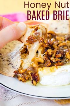 a hand holding a piece of bread with nuts on it and the words honey nut baked brie above it