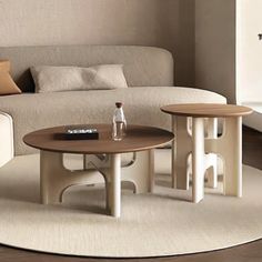 two coffee tables sitting on top of a white rug in front of a couch and table