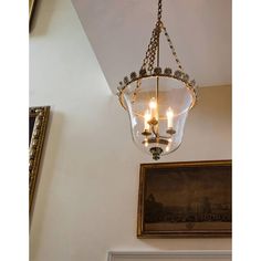 a chandelier hanging from the ceiling in a room with paintings on the wall