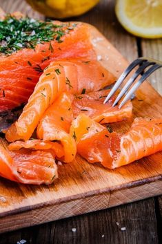 salmon on a cutting board with a fork and lemon wedges next to the fish