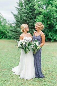 two women in dresses standing next to each other with flowers on their heads and holding bouquets