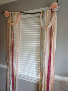 the curtains are hanging in front of the window with flowers on them and ribbons tied to it